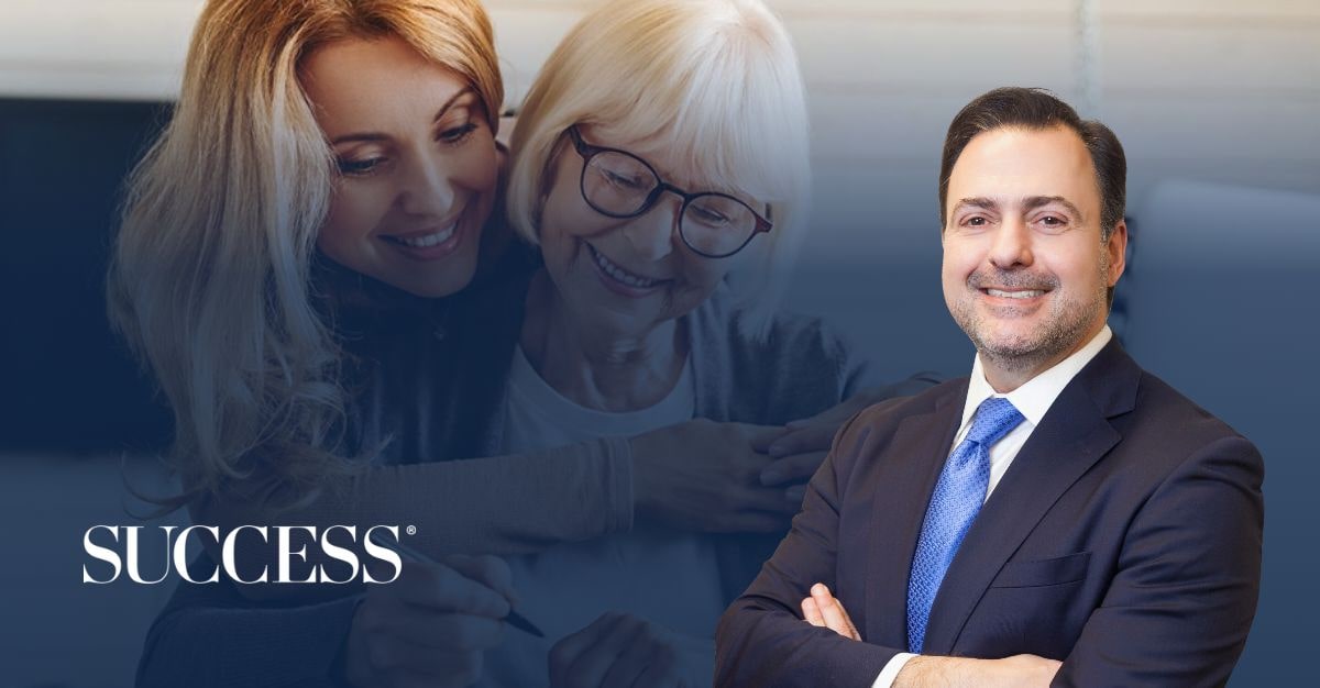 Professional portrait of attorney Asher Rubinstein smiling in a suit and blue tie, positioned in the foreground. In the background, a younger woman affectionately hugs an older woman with white hair and glasses, both smiling warmly. The SUCCESS magazine logo is displayed in the bottom-left corner.