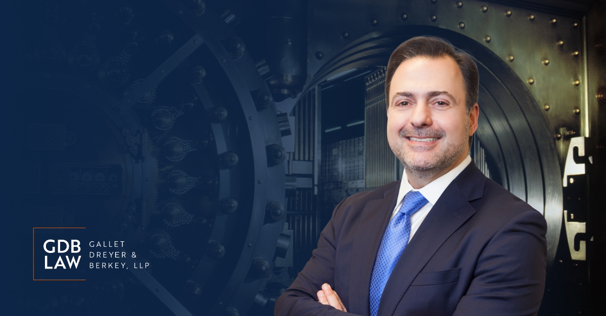 Asher Rubinstein in the right foreground of an image of a bank safe with the GDB logo in the bottom lefthand corner of the image.