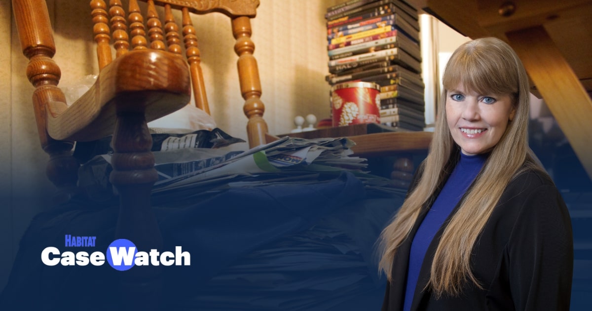 Michelle Quinn in the foreground of an image of a chair messily stacked with papers. 