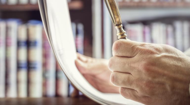 person examining documents with magnifying glass