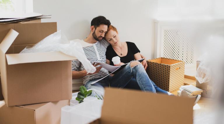 couple sitting on a couch surrounded by packing boxes