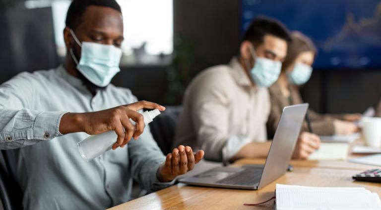 workers wearing masks and using sanitizer