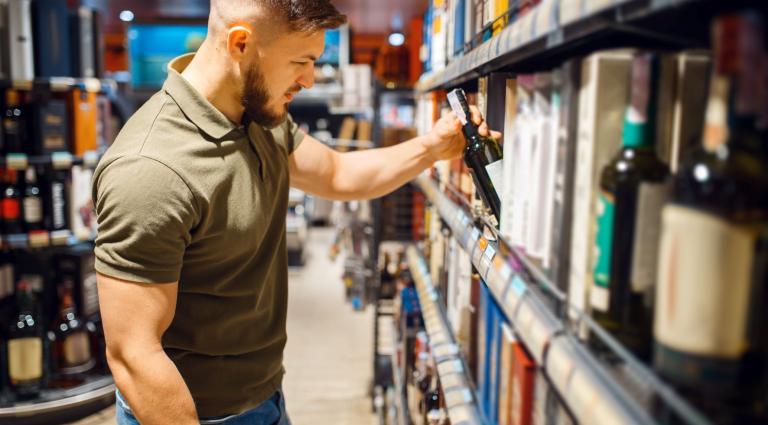 man choosing alcohol products in grocery store
