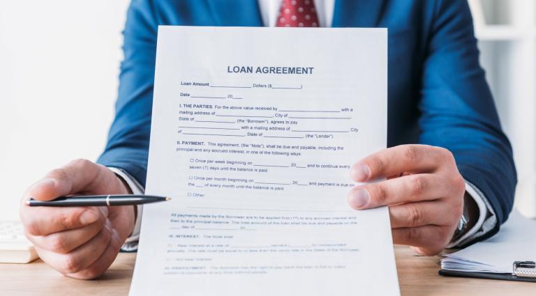 partial view of businessman pointing with pen at loan agreement