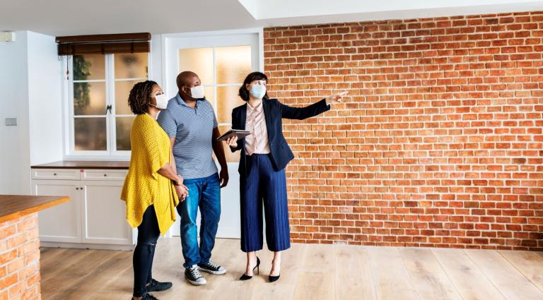 real estate agent and customers in face mask looking at an apartment