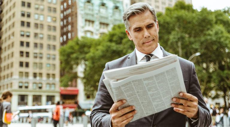 senior businessman reading newspaper in new york