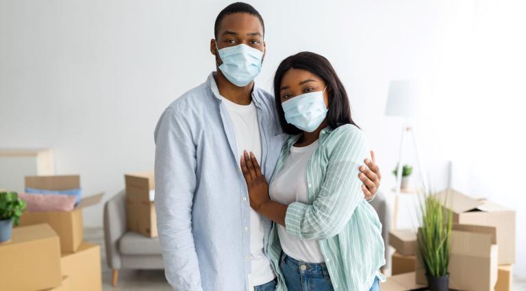 couple with masks on inside new apartment