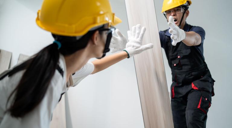 worker drops laminate board toward another worker