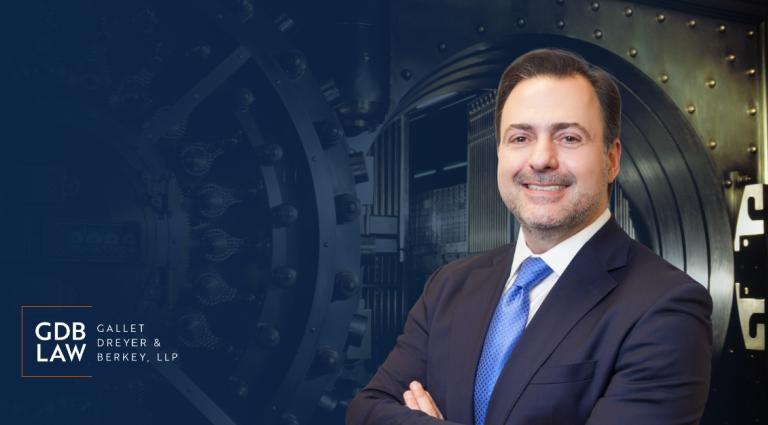Asher Rubinstein in the right foreground of an image of a bank safe with the GDB logo in the bottom lefthand corner of the image.