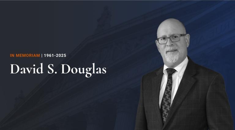 Headshot of David S. Douglas in front of a blue background.