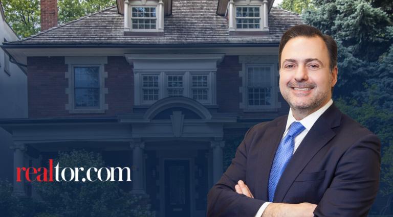 Headshot of Asher Rubinstein smiling with a background of a residential home. The Realtor.com logo appears on the left.”