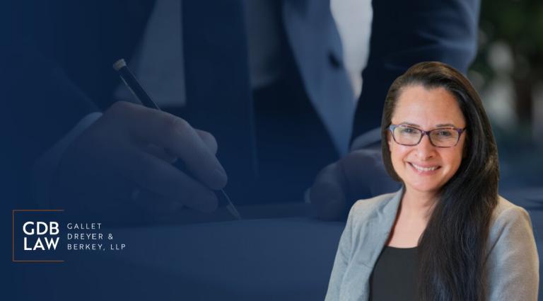 Headshot of Beth Gazes smiling against a blurred background of hands signing a document. The Gallet Dreyer & Berkey LLP logo appears on the left.