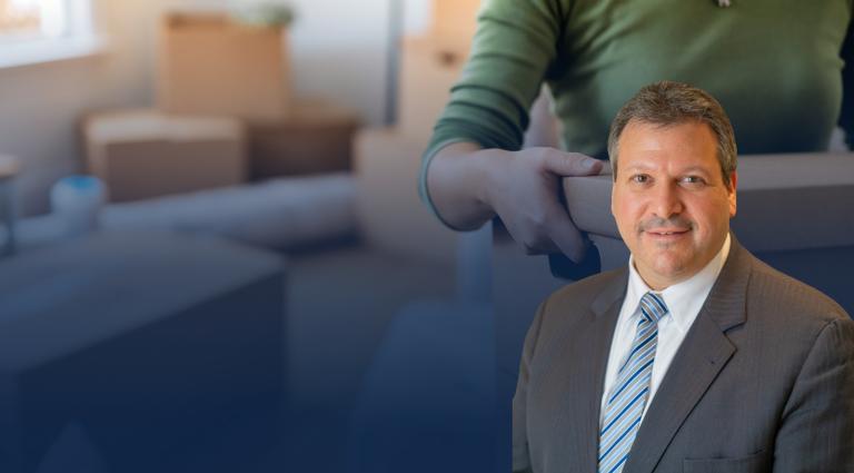 Joe Farca in a gray suit and blue striped tie, smiling at the camera. Behind him is a blurred image of a person carrying a cardboard moving box inside a home, suggesting a residential move or housing transition. The image conveys themes of real estate, landlord-tenant law, housing disputes, and property rights.