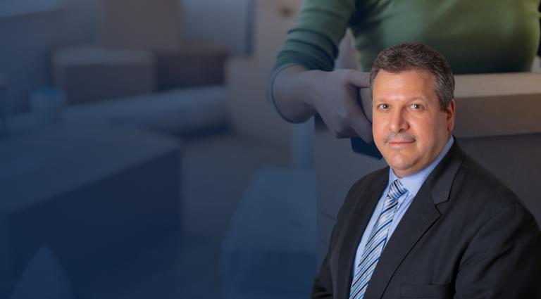 Joe Farca in a gray suit and blue striped tie, smiling at the camera. Behind him is a blurred image of a person carrying a cardboard moving box inside a home, suggesting a residential move or housing transition. The image conveys themes of real estate, landlord-tenant law, housing disputes, and property rights.